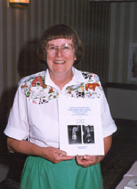 Doris Willoughby holding a copy of the book she wrote with Sharon Monthei.