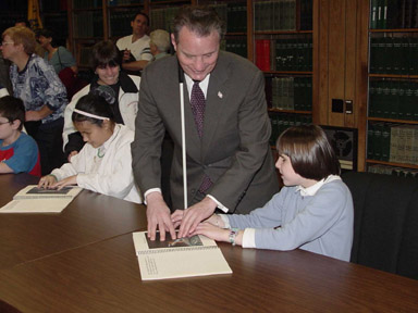 In the large conference room at the Center, students were able to examine copies of Touch the Universe.   Here Amy Herstein of Maryland inspects one copy of the book while President Maurer leans over Jenny Suchan of Maryland as they both examine another.