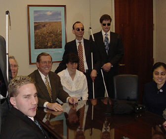 Senator Pete Domenici meets with Fred Schroeder(standing left) and Art Schreiber (seated center), president of the NFB of New Mexica, and other affiliate members.