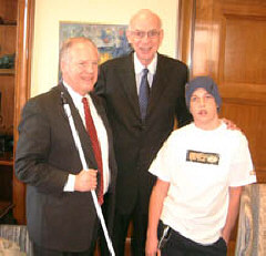 Ron Gardner, president of the NFB of Utah, and his son meet Senator Robert F. Bennett (center).