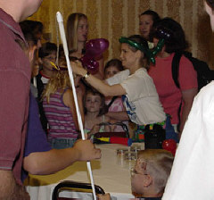 Jennifer Kennedy places a balloon animal crown on the head of Hannah Weatherd of Montana while others look on.