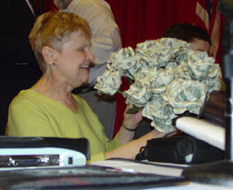 Diane McGeorge, perennial distributor of door prizes, holds a bouquet of roses provided as door prizes by the NFB of Utah.   Each rose was created from five $5 bills.