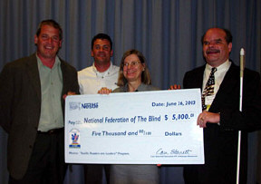 John Jell, national sales manager for the Nestle Company; Dan Roach, Nestle Vending Business Manager; Barbara Cheadle, president of the National Organization of Parents of Blind Children; and Kevan Worley, president of the National Association of Blind Merchants, stand together holding a large check replica.