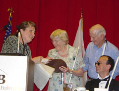 Ramona Walhof presents a plaque to Betty Woodward while her husband Bruce and Fred Schroeder look on.