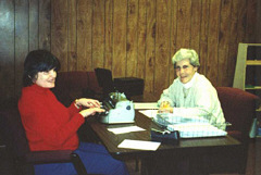 Bernice Lowder uses a Perkins Brailler while Aline Norris dictates information to her.
