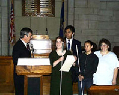 At a ceremony held October 22, 2003, in the Warner Chamber of the Nebraska state capitol, Governor Mike Johanns proclaims October as National Federation of the Blind Month.  Amy Buresh, Carlos Servan, and other NFB of Nebraska members accept the proclamation.