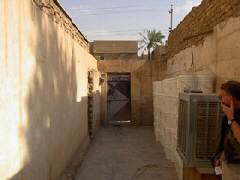The doorway into the office of the Iraqi organization assisting blind citizens.   An inspector from the Coalition Provisional Authority is standing beside a swamp cooler.