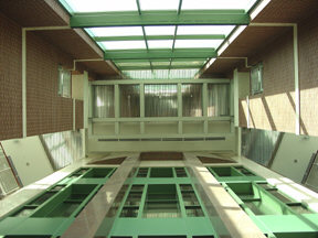 The glass elevator shafts, the railings of each floor, the metallic ceiling, and the glass front of the Institute can all be seen in this view taken from the first floor, looking up.