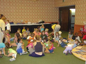 Children and NFB Camp staff members play on the floor/