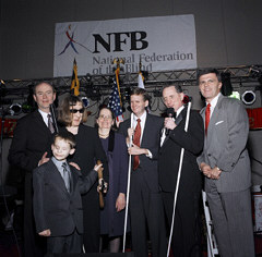 Just before the ribbon-cutting ceremony here are (left to right) Wally O.Dell, chairman and CEO of Diebold, Inc.;Jason Polanski, a seven-year-old from Maryland;Barbara Walker Loos,president of the American Action Fund for Blind Children and Adults;Mary Ellen Jernigan, NFB executive director of operations;Steve Marriott,senior vice president for cultural and special events, Marriott International, Inc.;Marc Maurer, president of the National Federation of the Blind; and Robet L. Ehrlich, Jr., governor of the state of Maryland.