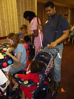 Leonida Besson in her stroller and Michael Besson at the craft table in the Braille Carnival room