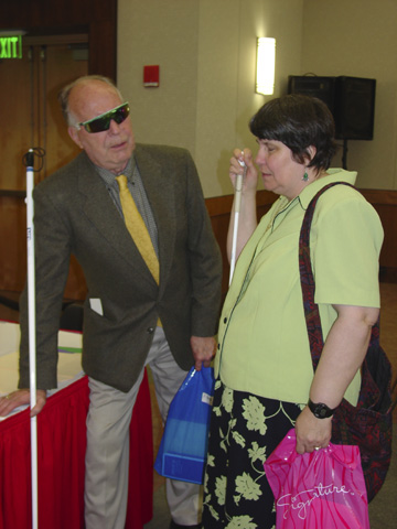 Ray McGeorge, vice president of the National Organization of the Senior Blind, and Ruth Sager, coordinator of senior services for Blind Industries and Services of Maryland, chat at a table.   McGeorge along with Duncan Larson (Colorado), Frank Lee  (Alabama), Virginia Mann  (Ohio), Janice Frost (Connecticut) ,Annette Grove (Illinois), Kyle Parrish (Washington State), and Hilda Jones (Kansas) attended the event and stayed for discussions to learn how their states could host similar senior fairs.