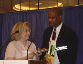 Anil Lewis presents an award to the Atlanta Journal-Constitution.   Virginia Everett, director, Information Services, accepts the plaque,