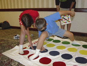 The Kenneth Jernigan Braille Carnival offered kids and their carnival buddies lots of activities and games.   Here two kids contort themselves to play Twister with a tactile difference, while a volunteer operates the spinner.