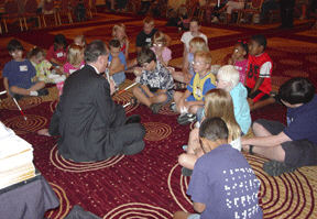 President Maurer sits on the floor, talking to the kids at the opening session of NOPBC activities.