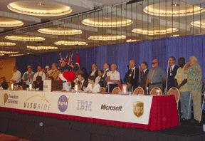 Dwight Sayer addresses the convention while veterans stand behind the head table on the dais.