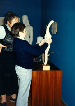 A museum visitor explores a copy of a Cycladic figurine, circa 2300 B.C.E.