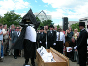Kevan Worley dressed as the Grim Reaper and  representing the Department of Education, destroys signs representing the hopes and dreams  of disabled Americans,