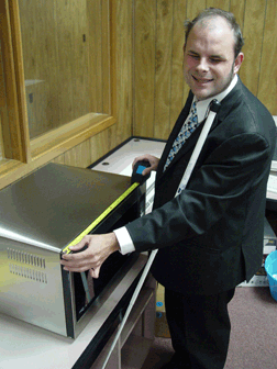 Mike Tindell, IBTC access technology specialist, measures a microwave with a talking tape measure.