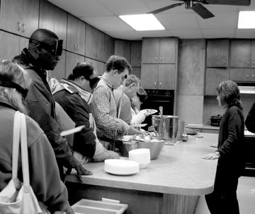 Students and staff chat as they work their way along the buffet line. Kelly Womack quietly supplies information and offers advice to those who ask for it. The students wearing sleepshades are learning that they don�t need residual vision to negotiate a buffet line.
