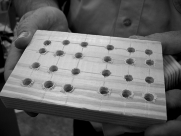 In shop class each student must cut a grid block and then incise horizontal and vertical lines across it every three-quarters of an inch using a tool called a scratch awl. At every intersection of two lines, the student must then drill a hole as deep as possible without breaking through the back and varying in size from five-sixteenths of an inch to three-quarters of an inch in diameter. The grid block may not be an object of beauty or complexity, but creating it teaches the student to measure accurately and drill holes of an exact size.