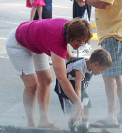 A mother and son step away from the march momentarily to explore an automatic sprinkler watering a bit of Texas.