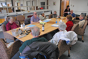 Ray McGeorge (center) teaches a group of seniors the Braille code. Tennis balls arranged in a six-cup muffin tin represent the dots in a Braille cell.