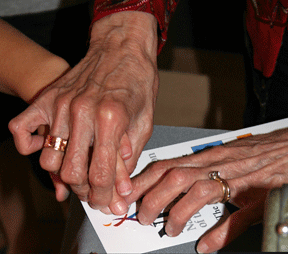 Dolores Reisinger’s hands guiding a student’s hands over Braille characters