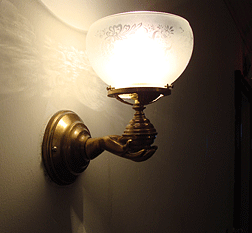 Lighting the staircase and the second floor are wall sconces comprised of a small human hand made of brass and holding a flared etched-glass shade and light bulb. These sconces were originally gas fixtures that have now been converted to electricity.