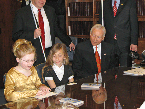 A child reads Braille to Senator Hatch.