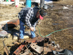Dan Treffer uses a torch to cut scrap metal into manageable pieces for sale.