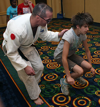 Greg DeWall, a blind judo instructor, teaches a girl to execute a leap.