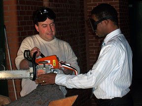 Mark Riccobono (left) explains the safe use of the chain saw to Oluyomi Koya.