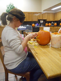 Kelly Newsom begins carving a pumpkin under sleepshades.