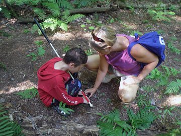 Thirteen-year-old Science Camp student Steven Crouch investigates soil in a wetland marsh with the help of Karen Taylor, a biology teacher and a science educator volunteer.