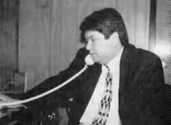 Curtis Chong is seated at his desk talking on the telephone.