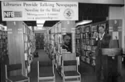 Image shows James Gashel at the podium in front of shelves of books)