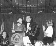 Photo of Ramona Walhof addressing the audience.  Allen Harris holds his Jocobus tenBroek
plaque; his wife, Joy, looks on, applauding.