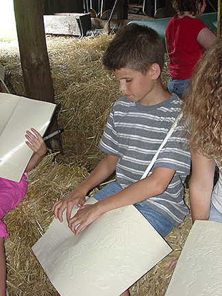 His cane resting on his shoulder, a young boy reads Braille.