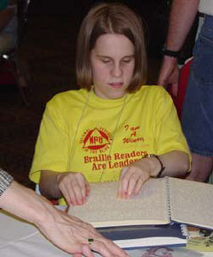 2002 most improved winnewr, Elizabeth Cavis of Tennessee, proudly wears her Braille Readers Are Leades t-shirt as she browses for Braille books at the flea market.