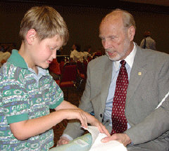 James Omvig, Treasurer of the Ameican Action  Fund for the Blind Children and Adults (AAF), looks at Braille books from the flea market with Dillon Lohr, a blind youngster from Indiana.  Omvig was one of about twenty mentors at the celebration.  The AAF donated several boxes of Braille books to the flea market, and several of the AAF officers, such as Omvig, also donated their time at the event as mentors.   Over two hundred people, at least fifty of whom were children, attended the anniversary celebration.