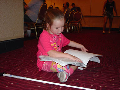 Anna Albury of the Bahamas finds an out-of-the-way corner to read her Braille book while her mom and aunt listen to reports about the past year's accomplishments at the 2004 Annual Meeting of the National Organizations of Parents of Blind Children (NOPBC) on Thirsday afternoon, July 1.