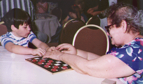 Adapted checker games are inexpensive and available from a variety of sources. Here, Louisiana youngster, Michael Taboada, gets some tips on the game from his opponent and blind mentor, Mary Brunoli, at a Federation function.