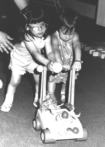 Playing with dolls is one of the earliest social playing experiences for most children. These two little girls are having a good time with their dolls while they learn important lessons about sharing and taking turns.