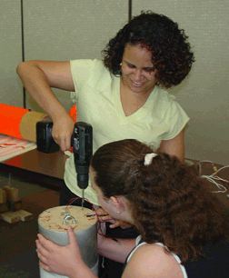 Mary Fernandez uses an electric screwdriver to complete a task in preparing the rocket for flight.