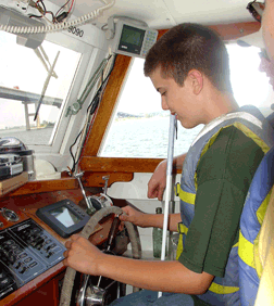 Nick Cocchiarella takes a turn at steering the Snow Goose on the bay.