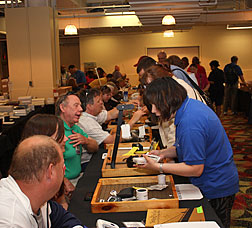 Seated within a ring of tables, volunteers show fellow members some of the aids and appliances for the blind sold by the NFB Store.