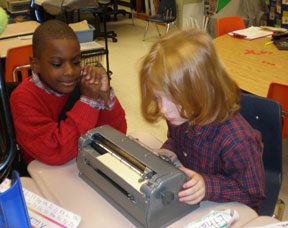 Two boys, Kendra's classmates, enjoy writing with the Brailler