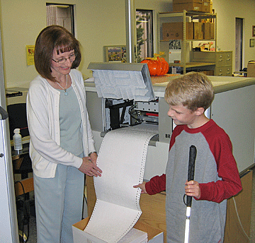 In 2007, Debra Bonde shows a young blind visitor one of her giant embossers.