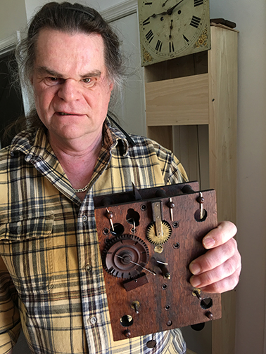 Fred Noesner holding a portion of repaired antique clock.